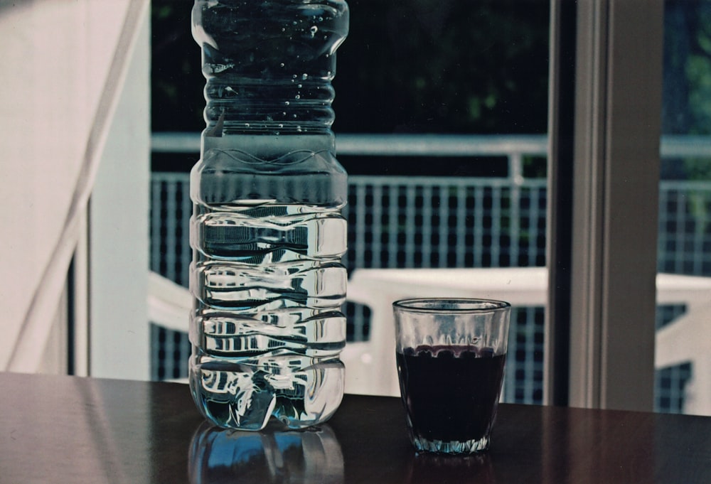 uma garrafa de vidro e um copo em uma mesa