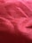 Close-up view of a red textured fabric surface with a grid-like pattern and visible fibers.