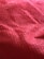 Close-up view of a red textured fabric surface with a grid-like pattern and visible fibers.