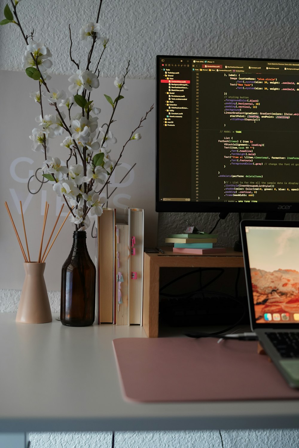 a vase of flowers next to a computer monitor