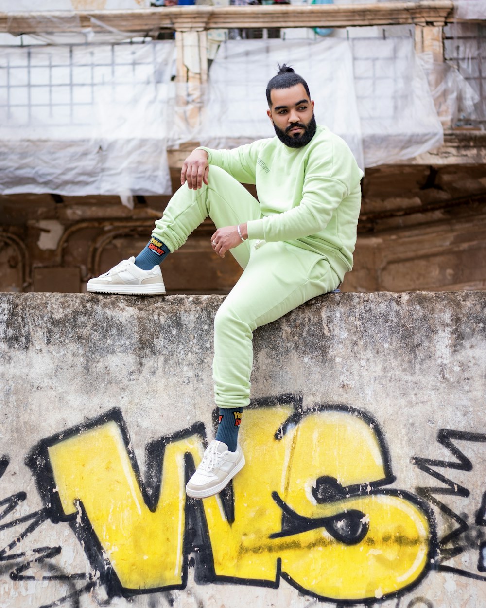 a man in a green suit sitting on a wall