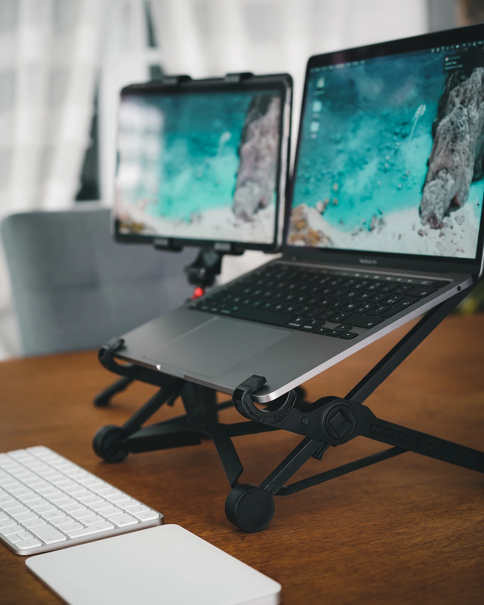 Laptop positioned on an adjustable stand with a second screen nearby