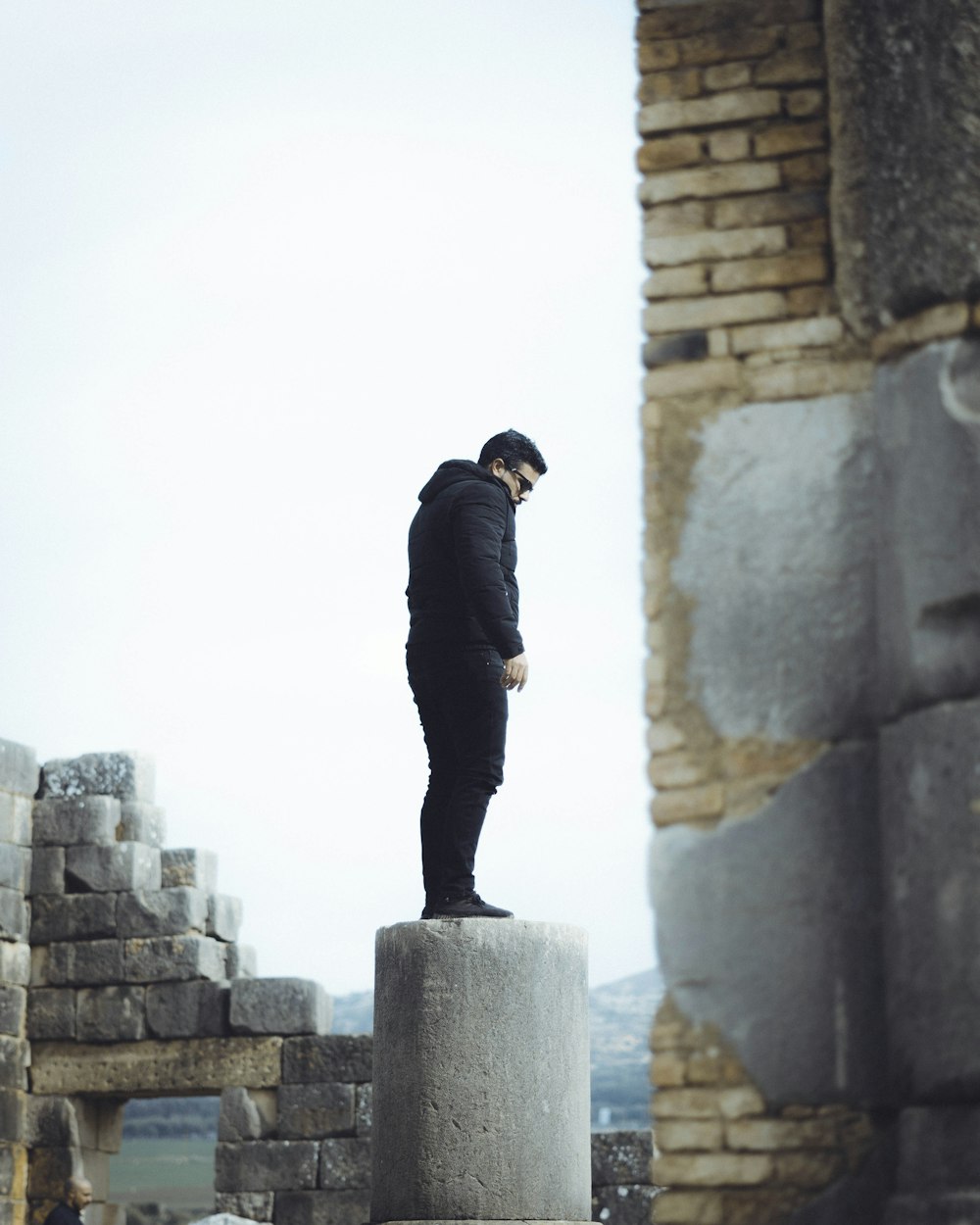 a man standing on a stone pillar