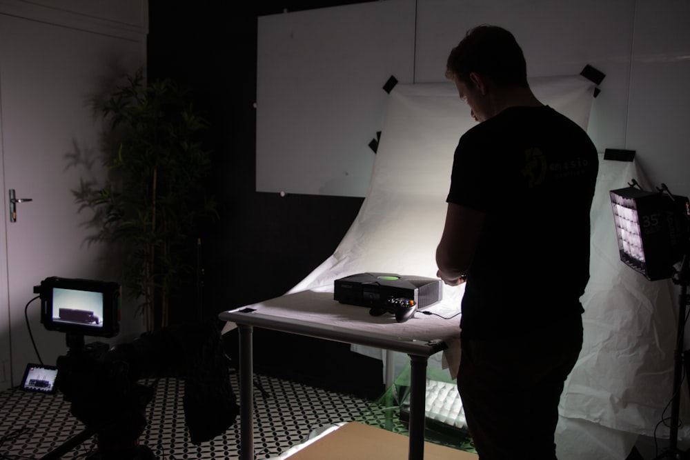 a man standing in front of a desk with a computer on it