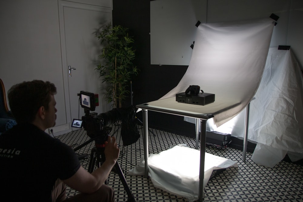 a person sitting at a table with a camera and a white umbrella