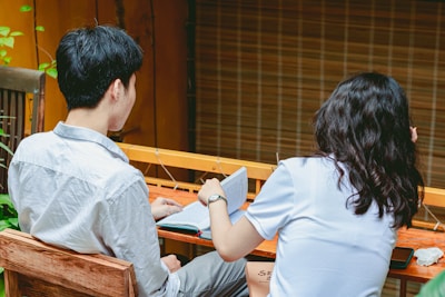 a man and a woman sitting at a table looking at a book