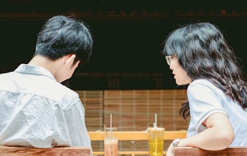 a man and woman sitting at a table with drinks