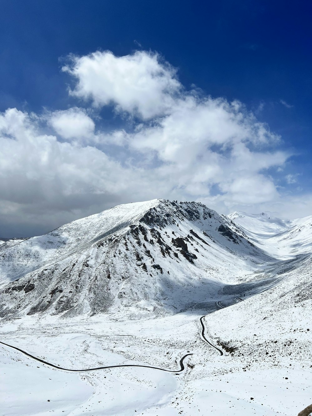 a snowy mountain with clouds