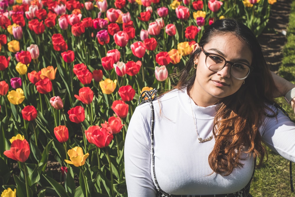 a person posing in front of a field of flowers