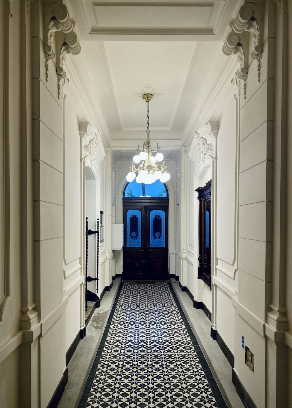 a hallway with a blue door and a chandelier