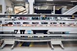 A factory setting with workers sorting apples on a conveyor belt. The space is well-lit with fluorescent lights and features industrial equipment. Workers are wearing protective clothing and hairnets.