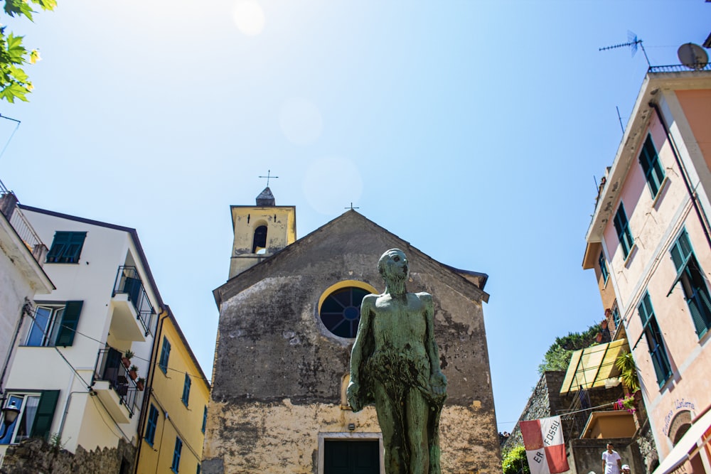 a statue of a person in front of a building with a cross on top