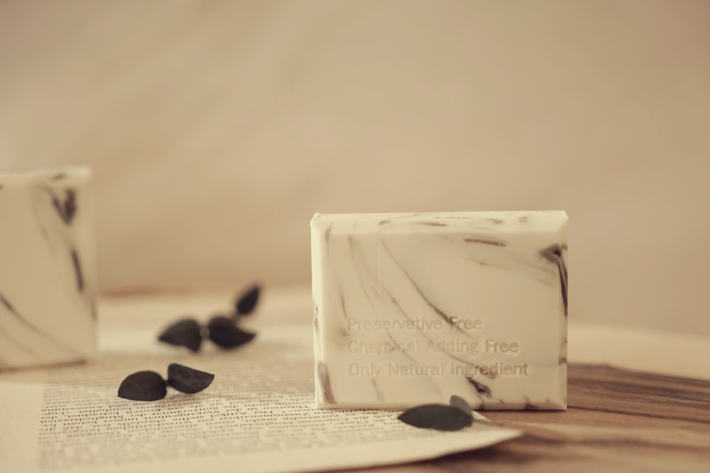 a white box with a label on it next to a pile of black pebbles