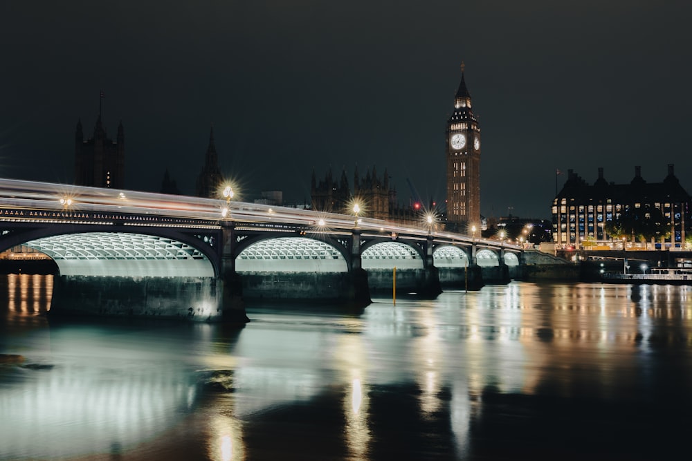 a bridge over a river with a clock tower in the background