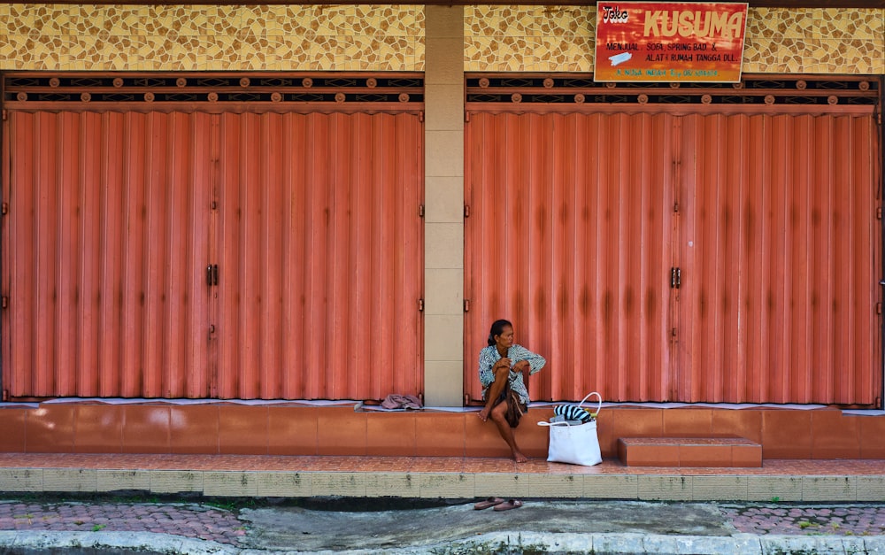 a person sitting on a curb next to a fire hydrant