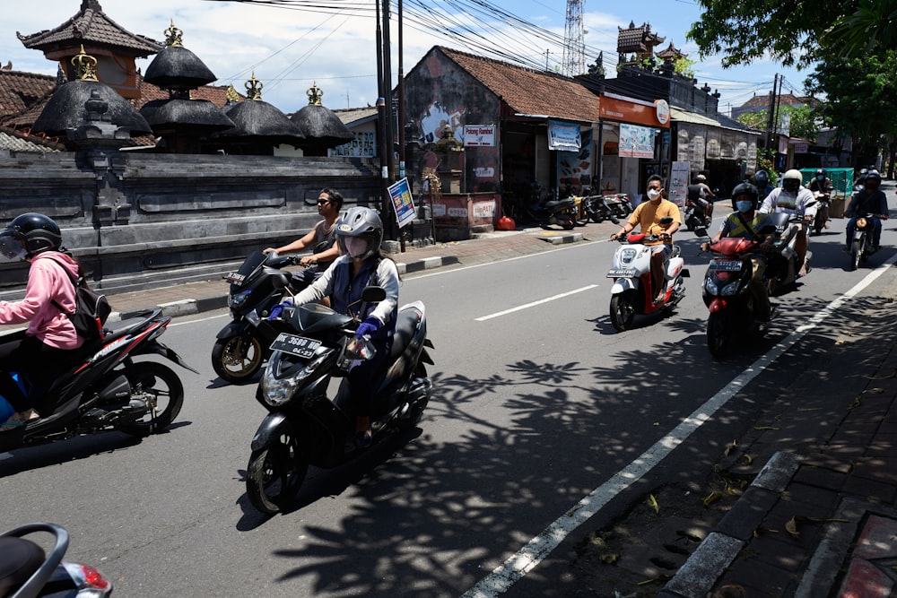 a group of people ride motorcycles down a street