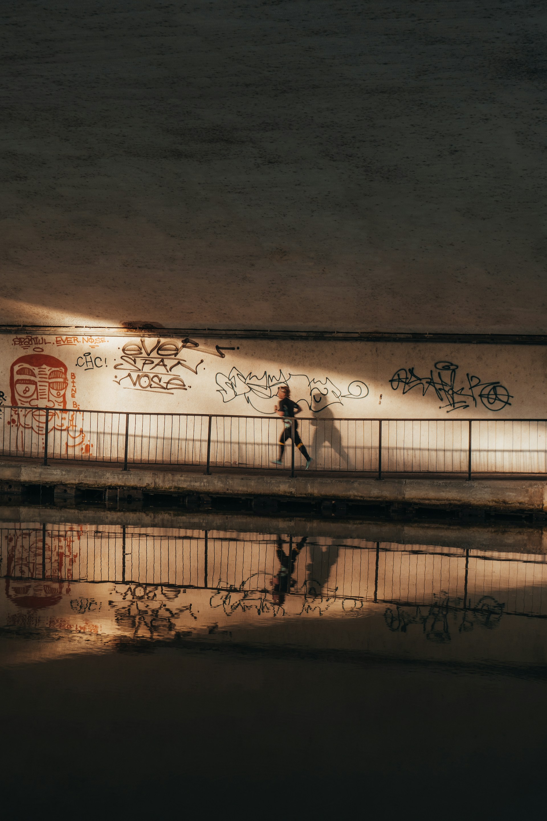 a couple of people walking on a bridge with graffiti on it
