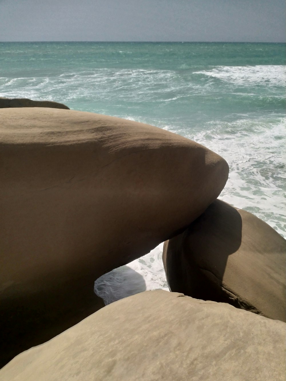 a person's foot on a rock by the ocean