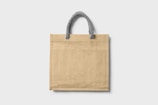 A plain beige tote bag with a textured surface, featuring a sturdy handle made of twisted grey rope.