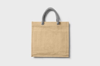A warm, minimalistic photo of a beige tote bag made of manta fabric with subtle boho embroidery.