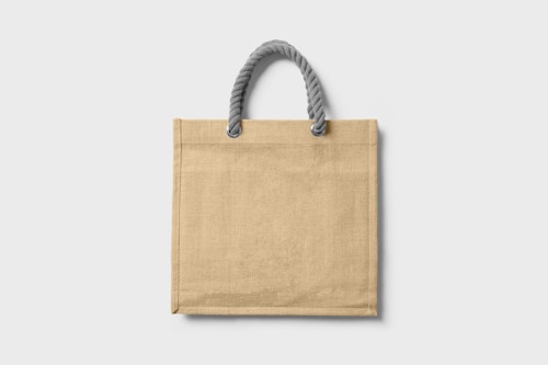 A plain beige tote bag with a textured surface, featuring a sturdy handle made of twisted grey rope.