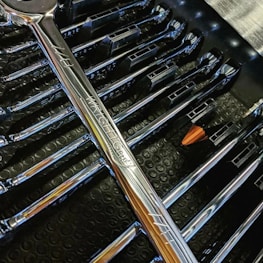 Close-up of tools neatly arranged on a workbench with a car in the background.