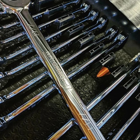 A close-up of a grease gun and oil filter wrench arranged neatly on a workbench.