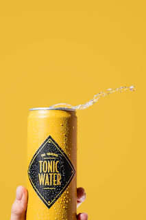 Close-up of a hand holding a Primewave can with a splash of water in the background.