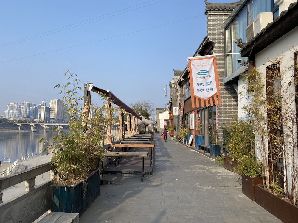 a sidewalk with tables and benches along it