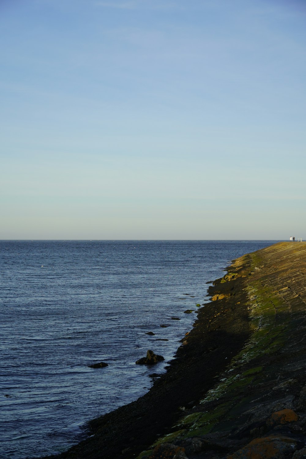 a rocky beach with a body of water in the background