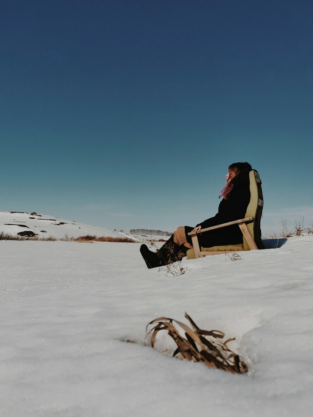 um homem sentado em uma cadeira na neve