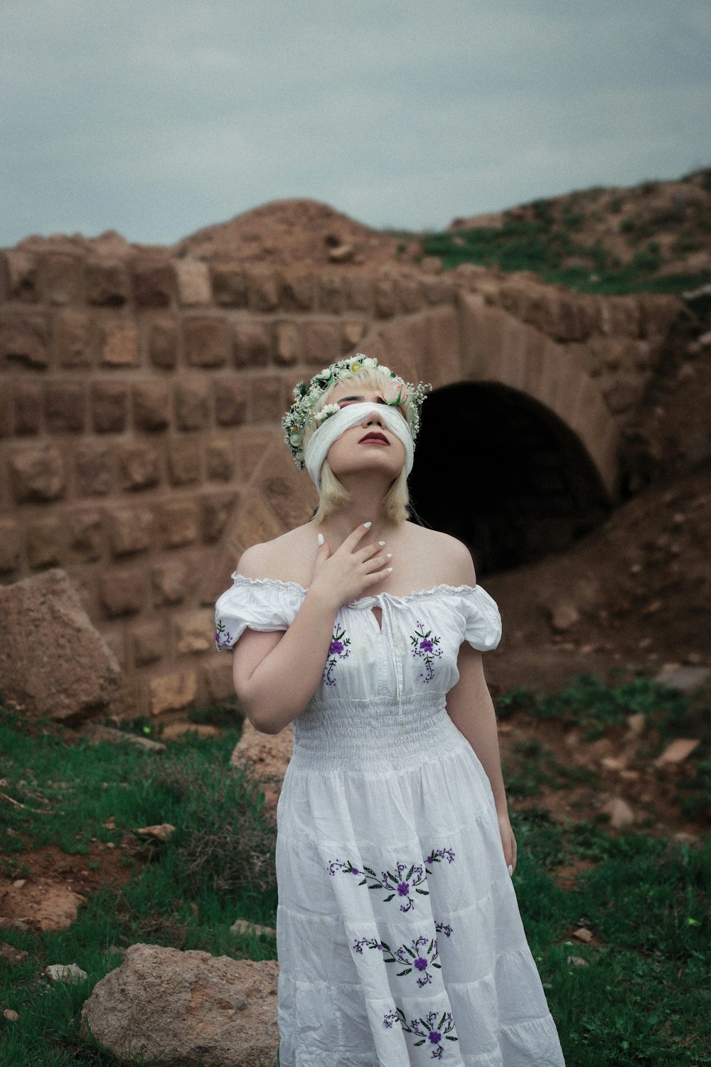 a girl standing in front of a stone wall with a stone arch