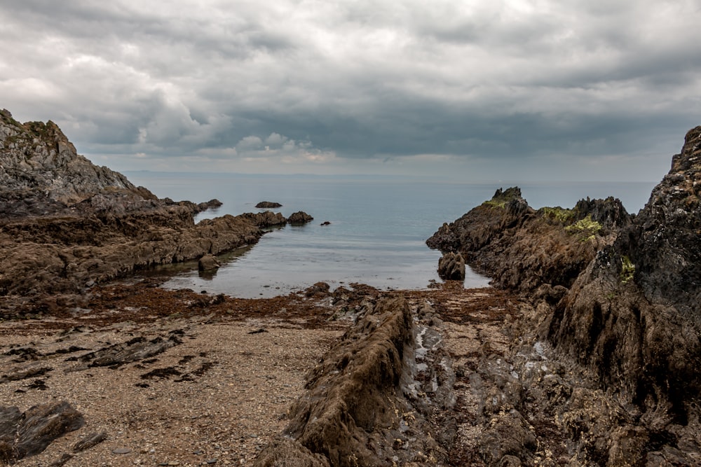 a rocky beach with a body of water in the background