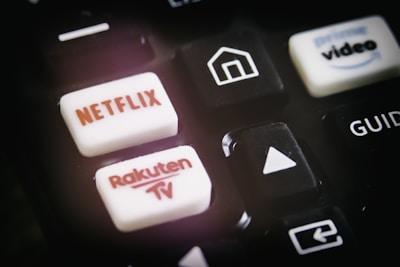A close-up of a remote control featuring buttons for various streaming services, including Netflix and Rakuten TV, along with other navigational buttons.