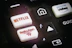 A close-up of a remote control featuring buttons for various streaming services, including Netflix and Rakuten TV, along with other navigational buttons.