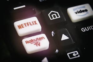 A close-up of a remote control featuring buttons for various streaming services, including Netflix and Rakuten TV, along with other navigational buttons.