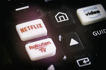 A close-up of a remote control featuring buttons for various streaming services, including Netflix and Rakuten TV, along with other navigational buttons.
