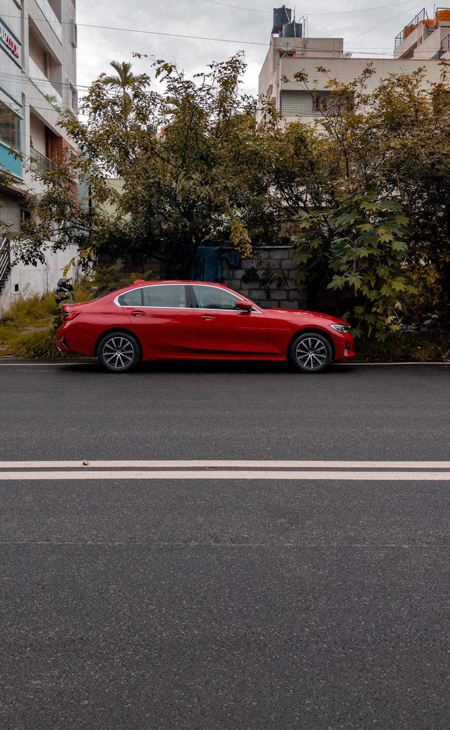 Red sedan on a tree-lined road
