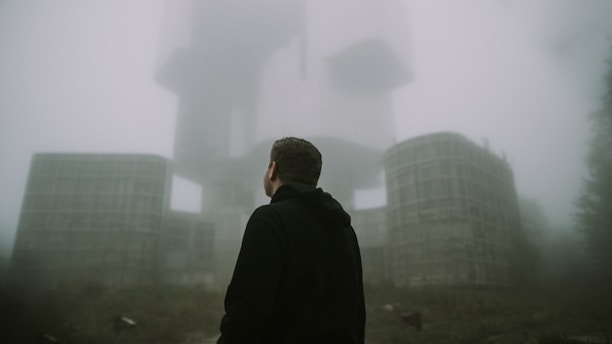 A shadowy figure resembling Milla Jovovich stands in front of a high-tech, red-lit Umbrella Corp. facility, with ominous black clouds swirling overhead.