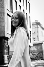 Black and white photo of a young woman surrounded by vintage fashion pieces and Baltimore street art.