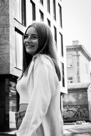Black and white photo of a young woman surrounded by vintage fashion pieces and Baltimore street art.