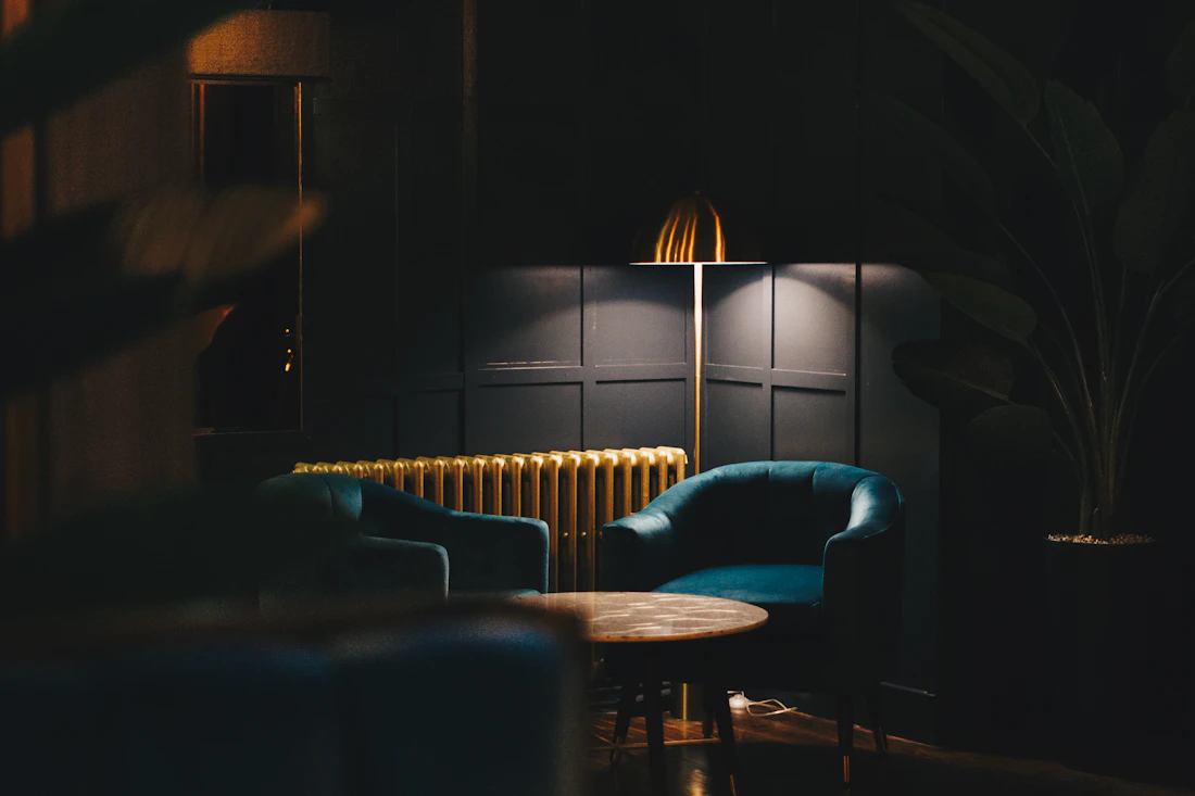 A calm, considered interior with a table, chairs and soft lamplight