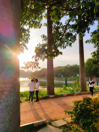 An authentic interaction between two friends caught mid-conversation in a sun-drenched park.