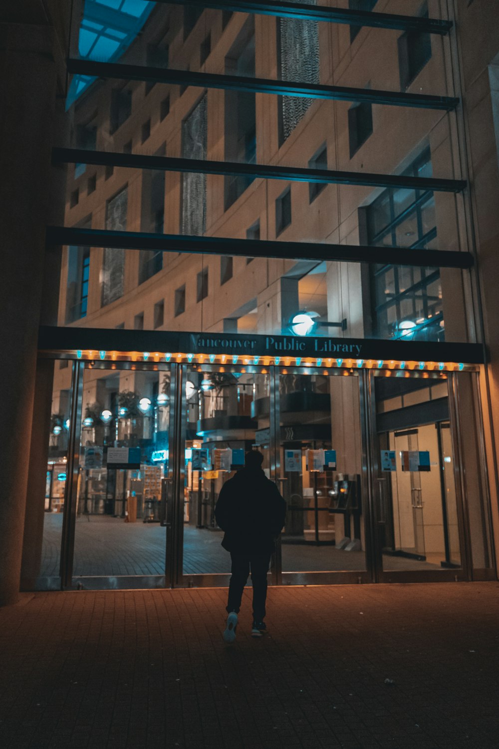 a person walking in front of a building with lights