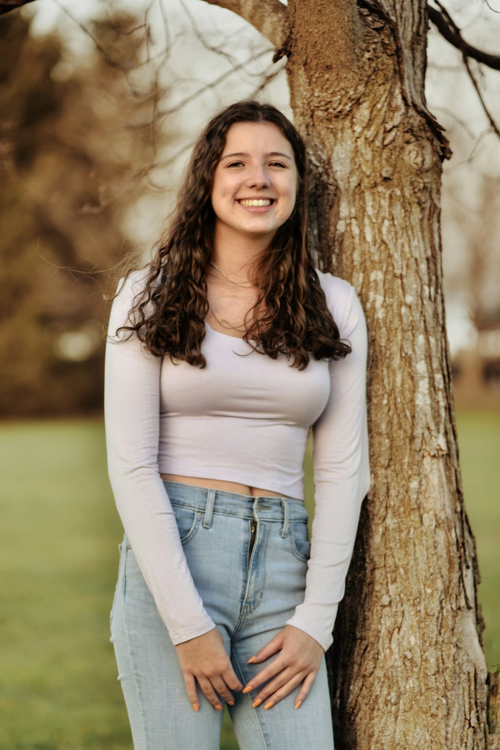 a woman standing next to a tree