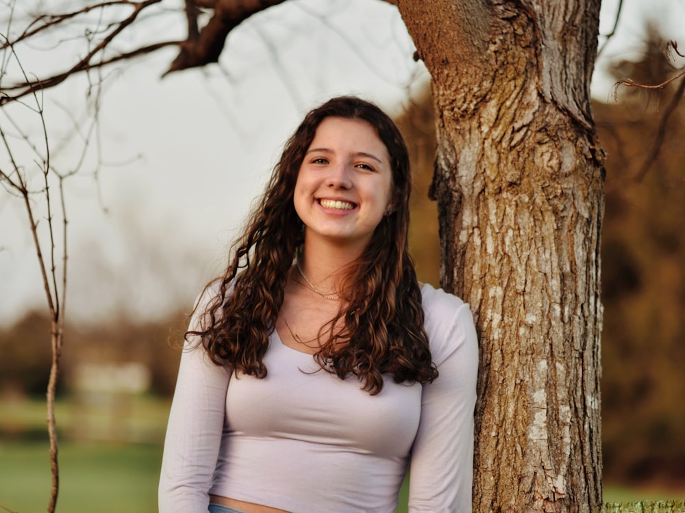 a woman standing next to a tree