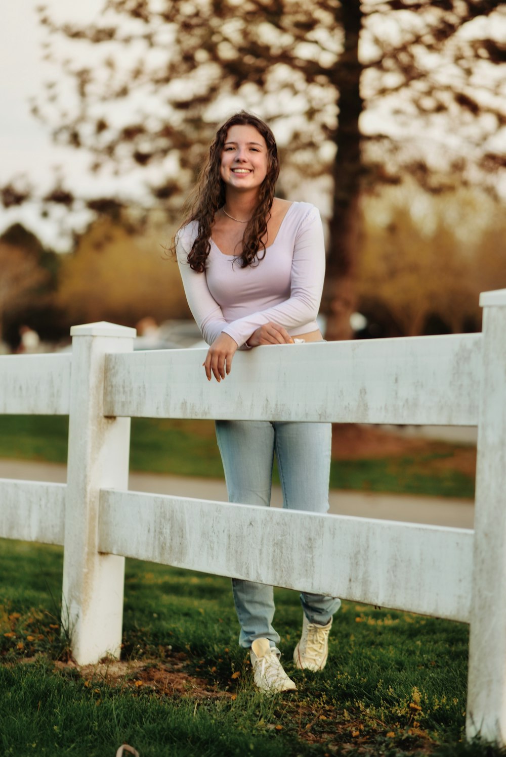 a woman leaning on a white fence