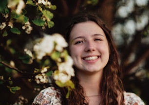 a woman smiling with flowers in the background
