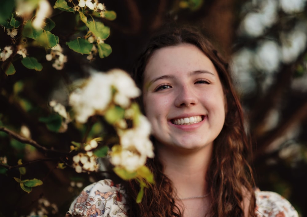 a woman smiling with flowers in the background