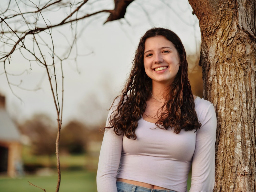 a woman standing next to a tree